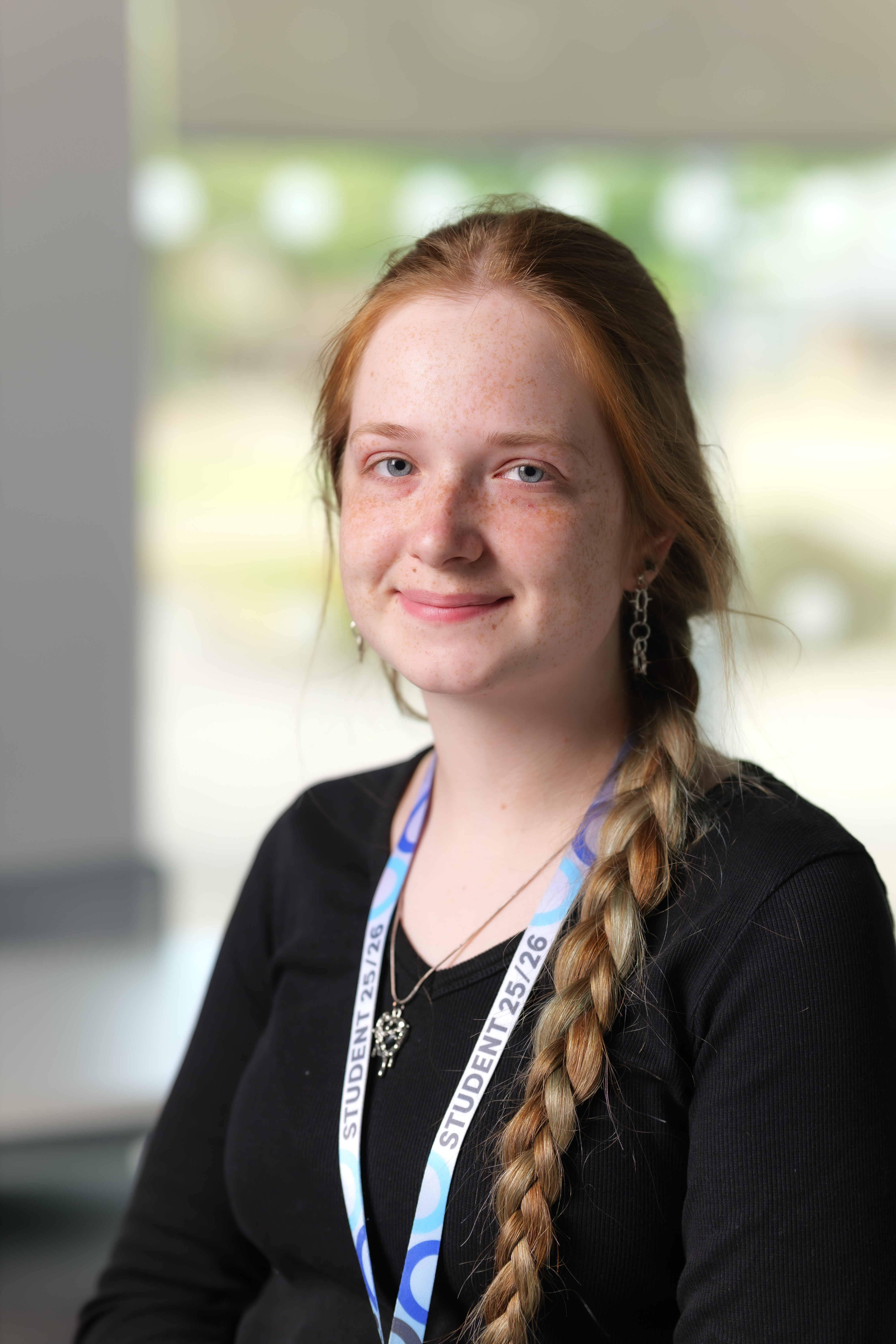 Student with long plait, wearing a black tshirt, smiling at the camera